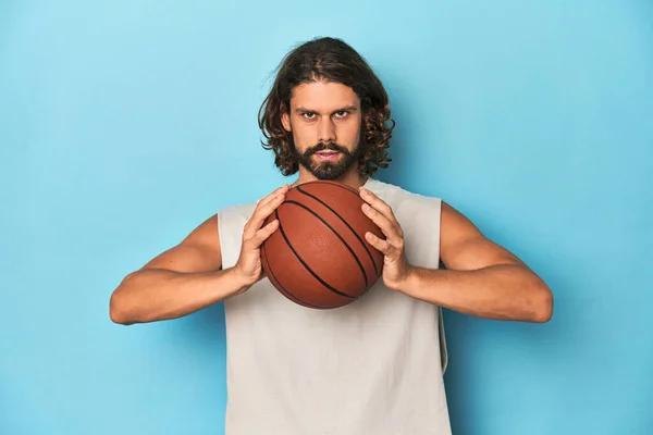 青いスタジオでバスケットボールを持っている長髪のひげ付き男 — ストック写真
