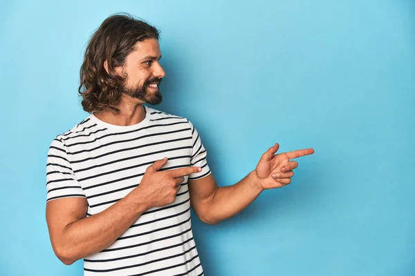 Bearded Man Striped Shirt Blue Backdrop Excited Pointing Forefingers Away — Stock Photo, Image