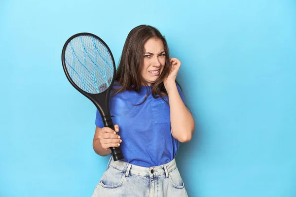 手で耳を覆う青い背景に電気バグバッパーを持つ女性 — ストック写真