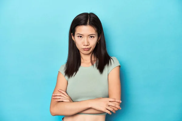 夏の緑のトップにアジアの女性 スタジオの背景 皮肉な表情でカメラを見ている不幸 — ストック写真