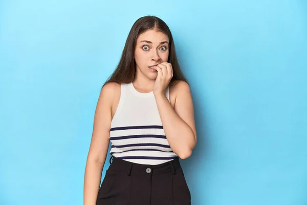 Woman Striped Top Posing Blue Studio Backdrop Biting Fingernails Nervous — Stock Photo, Image