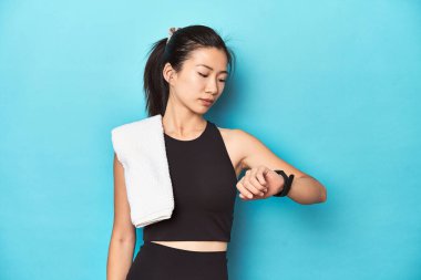 Asyalı sporcu kadın akıllı adamı kontrol ediyor, stüdyo arkaplanı.