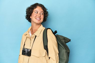 Klasik kameralı genç gezgin kadın gülümseyen, neşeli ve keyifli bir şekilde yana bakıyor..