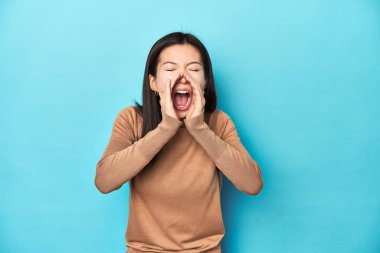 Kahverengi balıkçı yakalı genç bir Asyalı kadın, bağırıyor..