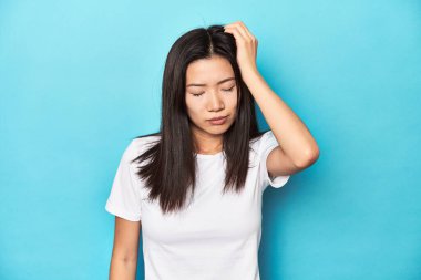 Beyaz tişörtlü, stüdyo fotoğraflı, yorgun ve uykulu bir Asyalı kadın..