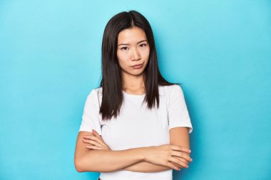 Beyaz tişörtlü genç Asyalı kadın, stüdyo fotoğrafı, şüpheli, belirsiz, seni muayene ediyor..