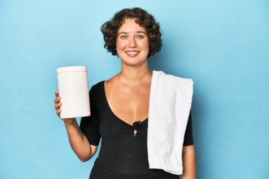 Havlu ve protein içeceği olan genç sporcu kadın, stüdyo çekimi..