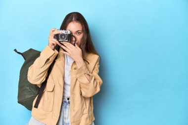Gezgin kadın mavi renkli eski bir kamerayla fotoğraf çekiyor..