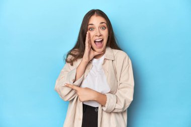 Mavi arka planda tişörtlü şık genç bir kadın dedikodu yapıyor, bir şeyleri bildiriyor..