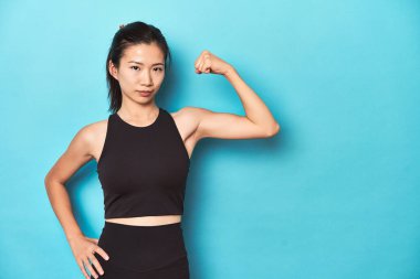 Asyalı sporcu kadın kol hareketleriyle güç gösteriyor. Stüdyo çekimi..