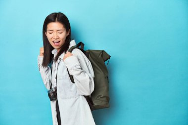 Genç Asyalı gezgin maceraları yakalamaya hazır zaferden sonra yumruğunu kaldırıyor, kazanan konsept.