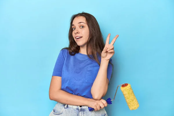 Young Woman Yellow Paint Roller Blue Background Showing Number Two — Stock Photo, Image