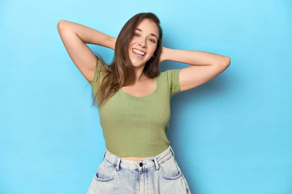 Jonge Blanke Vrouw Een Groene Top Een Blauwe Achtergrond Stretching — Stockfoto