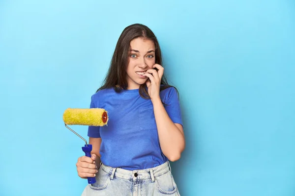Young Woman Yellow Paint Roller Blue Background Biting Fingernails Nervous — Stock Photo, Image