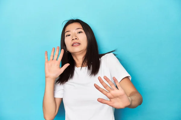 年轻的亚洲女人穿着白色的T恤 演播室里的镜头 被一种迫在眉睫的危险吓坏了 — 图库照片