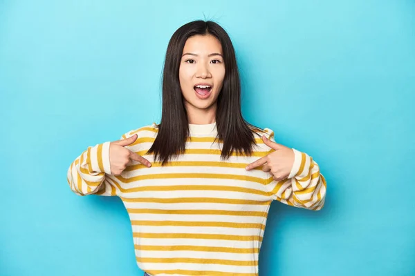 Asian Woman Striped Yellow Sweater Surprised Pointing Finger Smiling Broadly — Stock Photo, Image