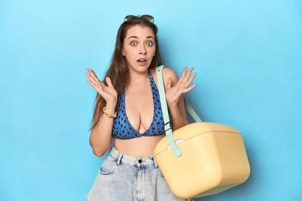 Kobieta Bikini Przenośną Chłodnicą Plażową Niebieskie Studio Zaskoczona Zszokowana — Zdjęcie stockowe