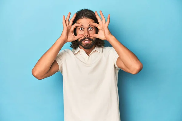Hombre Pelo Largo Polo Blanco Estudio Azul Mantener Los Ojos —  Fotos de Stock