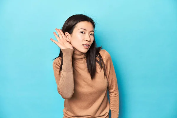 穿着棕色毛衣的年轻亚洲女人 想听一些闲话 — 图库照片