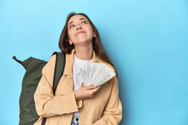 ブルーにドル紙幣を保持するバックパックを持つ旅行女性 — ストック写真