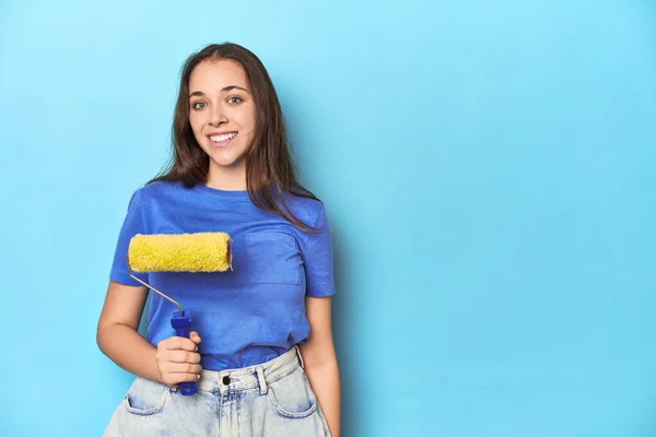 Jovem Mulher Com Rolo Tinta Amarela Fundo Azul Feliz Sorridente — Fotografia de Stock