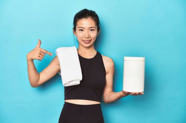 Protein şişesi olan genç Asyalı sporcu, spor salonu düzeneği, gömlek fotokopi alanını gösteren kişi, gururlu ve kendinden emin.