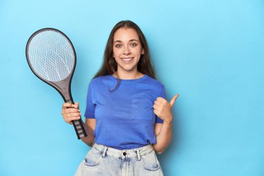 Mavi arka planda elektrikli böcek saplı bir kadın gülümsüyor ve başparmağını kaldırıyor.