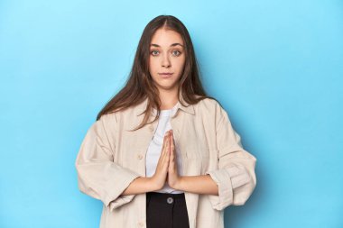 Mavi arkaplanlı şık genç bir kadın. Dua ediyor, bağlılık gösteriyor. İlahi ilham arayan dindar biri..