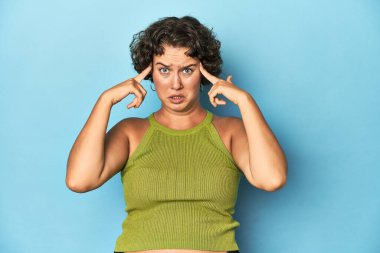 Kısa saçlı, genç, beyaz bir kadın bir işe odaklanmış, parmaklarını işaret ediyor..