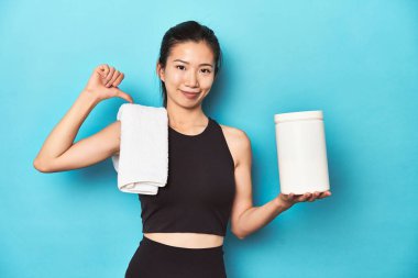 Protein şişesi ve spor salonu düzeniyle genç Asyalı sporcu, gururlu ve kendinden emin hissediyor, örnek olarak.