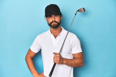Golf sopası ve şapkası olan uzun saçlı bir golfçü, kuşkulu ve kararsız hissediyor..