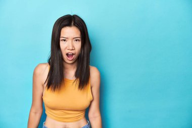 Yazın sarı bluzlu Asyalı kadın, stüdyo kurulumu, çok kızgın, öfke konsepti, hayal kırıklığına uğramış.