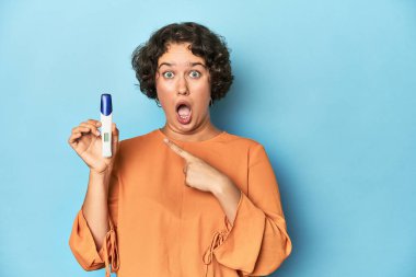 Hamilelik testi yapan genç bir kadın. Stüdyo geçmişi yan tarafı gösteriyor.