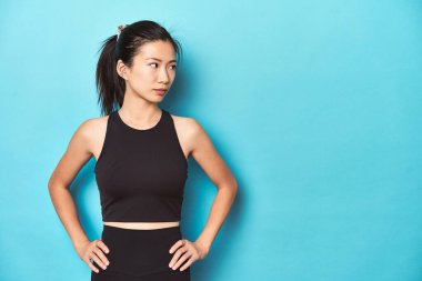 Genç Asyalı sporcu, stüdyo fotoğrafı, mavi arka planda..