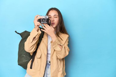 Gezgin kadın mavi renkli eski bir kamerayla fotoğraf çekiyor..