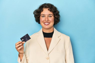 Beyaz takım elbiseli genç bir kadın kredi kartı tutuyor, stüdyo fotoğrafı..