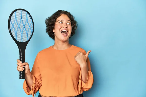 電動蚊のラケットを持つ若い女性 親指で電気蚊のラケットポイントを離れて 笑いとケアフリー — ストック写真