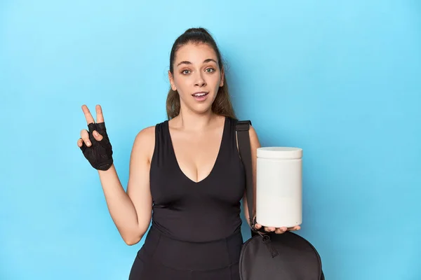 Young Woman Holding Protein Bottle Sporty Setting Showing Number Two — Stock Photo, Image