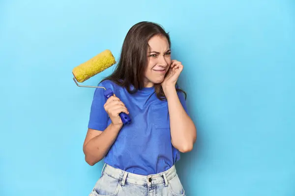 Young Woman Yellow Paint Roller Blue Background Covering Ears Hands — Stock Photo, Image