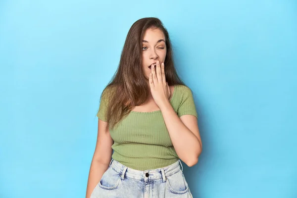 Mavi Arka Planda Yeşil Bluzlu Beyaz Bir Kadın Esniyor Ağzı — Stok fotoğraf