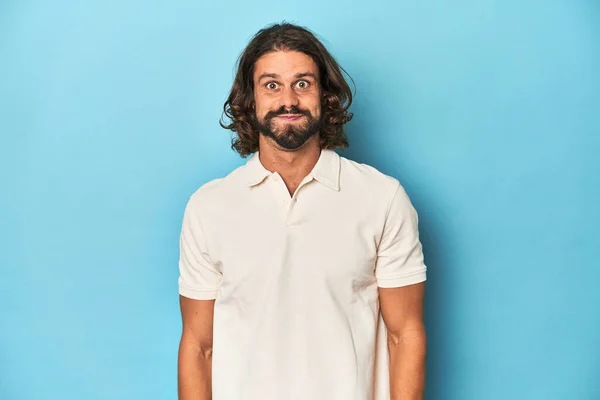 Long Haired Man White Polo Blue Studio Blows Cheeks Has — Stock Photo, Image