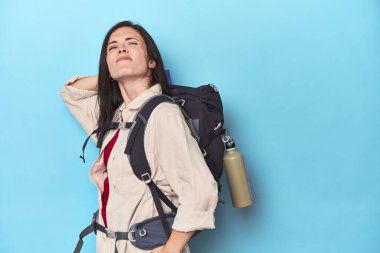 Sırt çantalı maceraperest kadın kafasının arkasına dokunuyor, düşünüyor ve bir seçim yapıyor..