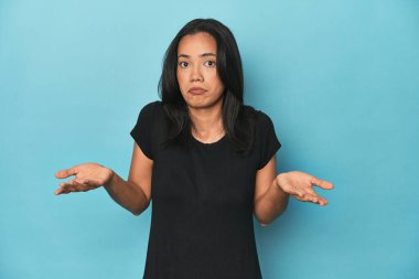 Mavi stüdyodaki Filipinli genç kadın jestini sorgulamak için omuz silkiyor..