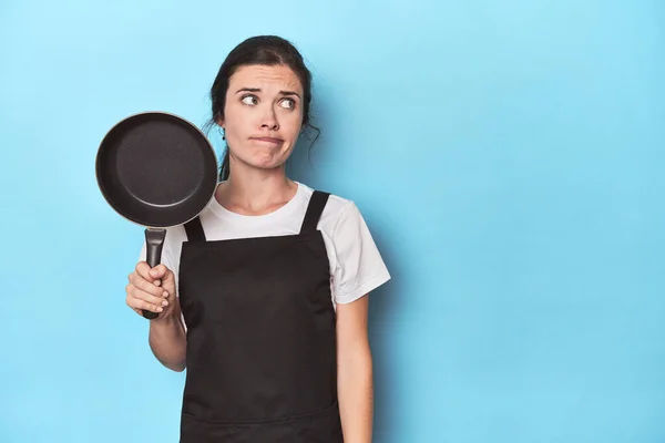 Woman Apron Pan Blue Background Confused Feels Doubtful Unsure — Stock Photo, Image