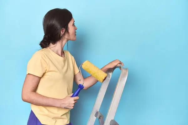 Mujer Pintando Una Pared Azul Desde Una Escalera — Foto de Stock