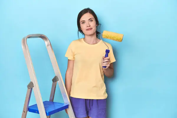 Mulher Pintando Uma Parede Azul Uma Escada — Fotografia de Stock