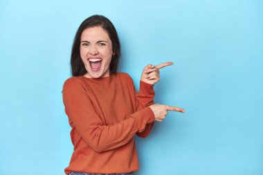 Mavi arka planda genç beyaz bir kadın işaret parmaklarıyla fotokopi alanını işaret ederek heyecan ve arzusunu ifade ediyor..