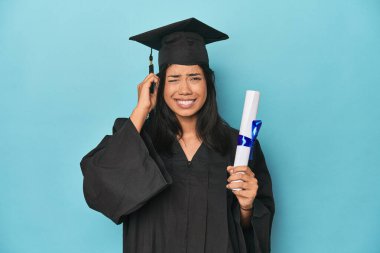Mavi stüdyo diplomasıyla Filipinli. Kulakları elleriyle kapatmış..
