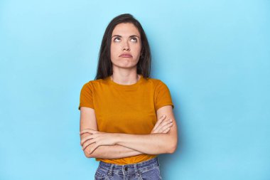 Mavi arka plandaki genç beyaz kadın tekrarlanan bir görevden bıktı..