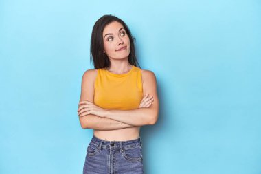 Mavi arka planda hedeflere ve amaçlara ulaşmayı hayal eden beyaz bir kadın.